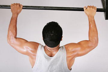 Image showing Reaching Goal: Strong man doing pull-ups on a bar in a gym