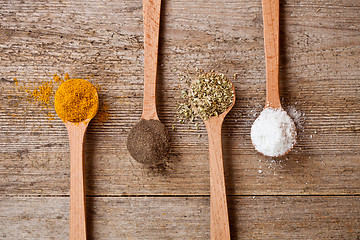 Image showing curry, pepper, oregano and cooking salt in wooden spoons 
