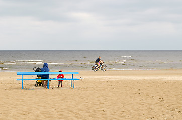 Image showing woman with kid sit on bench bicycle sea coast line 