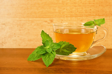 Image showing Herbal tea in a glass cup with mint on a wooden board