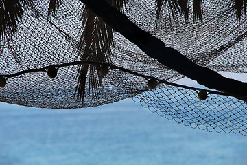 Image showing View of morning sea with palm tree silhouettes and fishing nets