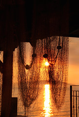 Image showing Wonderful sea sunset with palm tree silhouettes and fishing nets