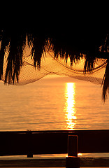 Image showing Wonderful sea sunset with palm tree silhouettes and fishing nets