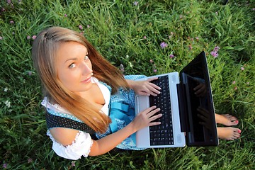 Image showing Bavarina Woman in Flowering Meadow with Laptop from above