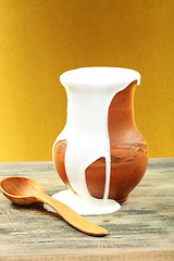 Image showing Clay pot with cream and spoon.