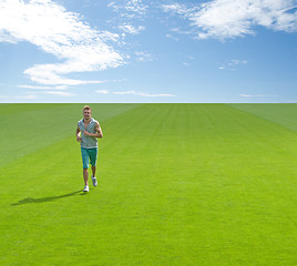 Image showing Sporty young man running on green field