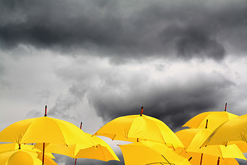 Image showing yellow umbrellas on cloudy background