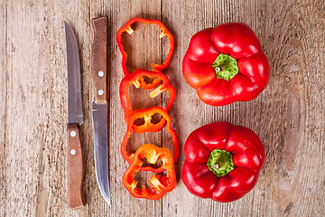 Image showing red bell peppers and old knifes 