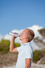 Image showing young man ist drinking water summertime dune beach sky