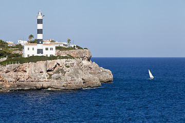 Image showing white lighthouse on rocks in the sea ocean water sky blue