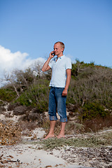 Image showing young man outside in summer on beach with mobile phone