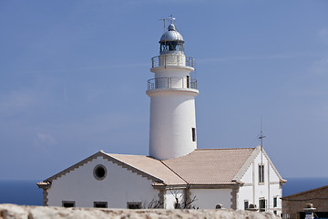 Image showing white lighthouse on rocks in the sea ocean water sky blue