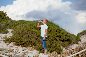 Image showing young man ist drinking water summertime dune beach sky