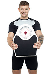 Image showing Smart young fit male showing weighing machine