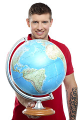 Image showing Guy with tattoos showing globe to camera