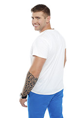 Image showing Young smiling man with tattoo on hand turning back