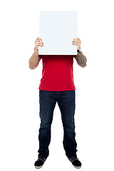 Image showing Man hiding his face behind blank white ad board