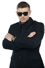Image showing Young stylish bouncer in a black suit, arms folded