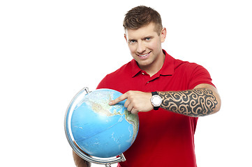 Image showing Cool guy holding and pointing at the globe