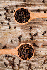 Image showing black pepper and cloves in wooden spoons