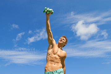 Image showing Happy fit guy holding his t-shirt