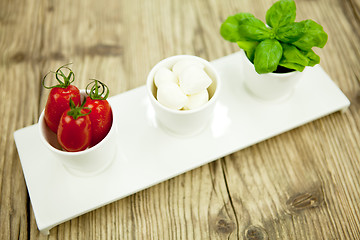 Image showing tasty tomatoes mazarella and basil on plate on table