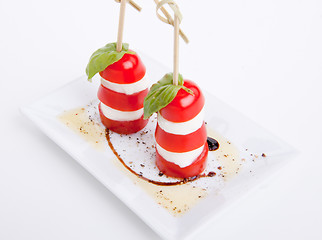 Image showing tasty tomatoe mozzarella salad with basil on white 