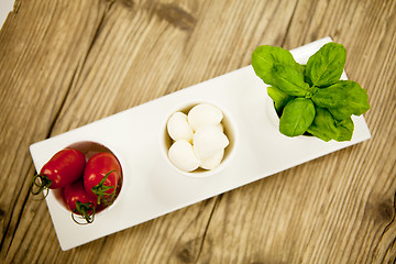 Image showing tasty tomatoes mazarella and basil on plate on table