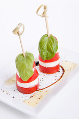 Image showing tasty tomatoe mozzarella salad with basil on white 