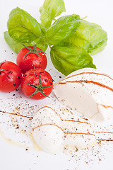 Image showing tasty tomatoe mozzarella salad with basil on white 