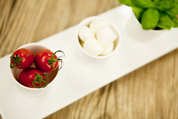 Image showing tasty tomatoes mazarella and basil on plate on table