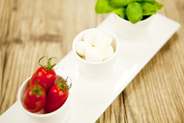 Image showing tasty tomatoes mazarella and basil on plate on table