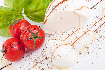 Image showing tasty tomatoe mozzarella salad with basil on white 