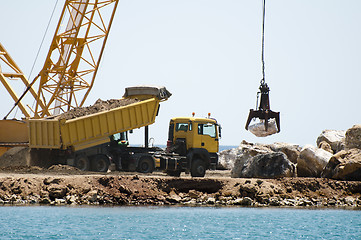 Image showing Building a dike. Cranes and excavator put stones