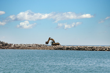 Image showing Building a dike. Excavator put stones