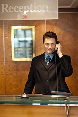 Image showing Profile shot of a handsome receptionist on the phone