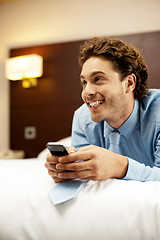 Image showing Man holding cellphone and lying on bed, relaxed