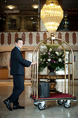 Image showing Handsome concierge pushing the luggage cart