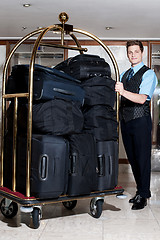 Image showing Concierge with a pile of bags in luggage cart