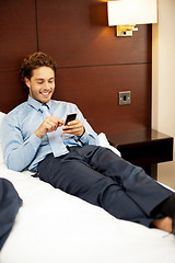 Image showing Man resting in luxurious bed and messaging