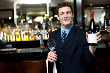 Image showing Cheerful executive posing with a bottle of wine