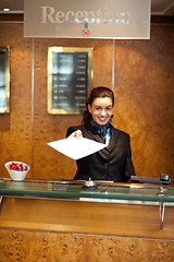 Image showing Female receptionist handing over check-out papers