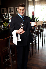 Image showing Man posing with a bottle of wine in restaurant