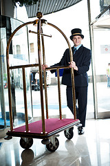 Image showing Profile shot of a doorman holding a cart