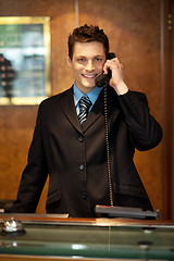 Image showing Cheerful front desk executive attending phone call