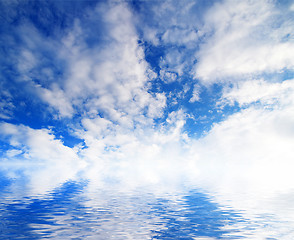 Image showing white fluffy clouds with rainbow in the blue sky