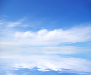 Image showing white fluffy clouds with rainbow in the blue sky