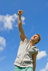 Image showing Smiling young man with his arm raised in joy