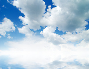 Image showing white fluffy clouds with rainbow in the blue sky