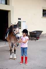 Image showing Little girl ready for a horseback riding lesson